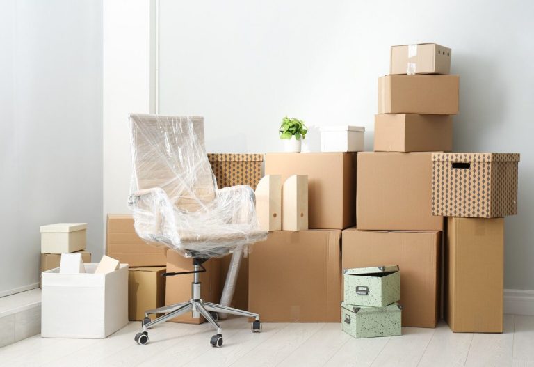 A room with packed boxes and a wrapped up office chair