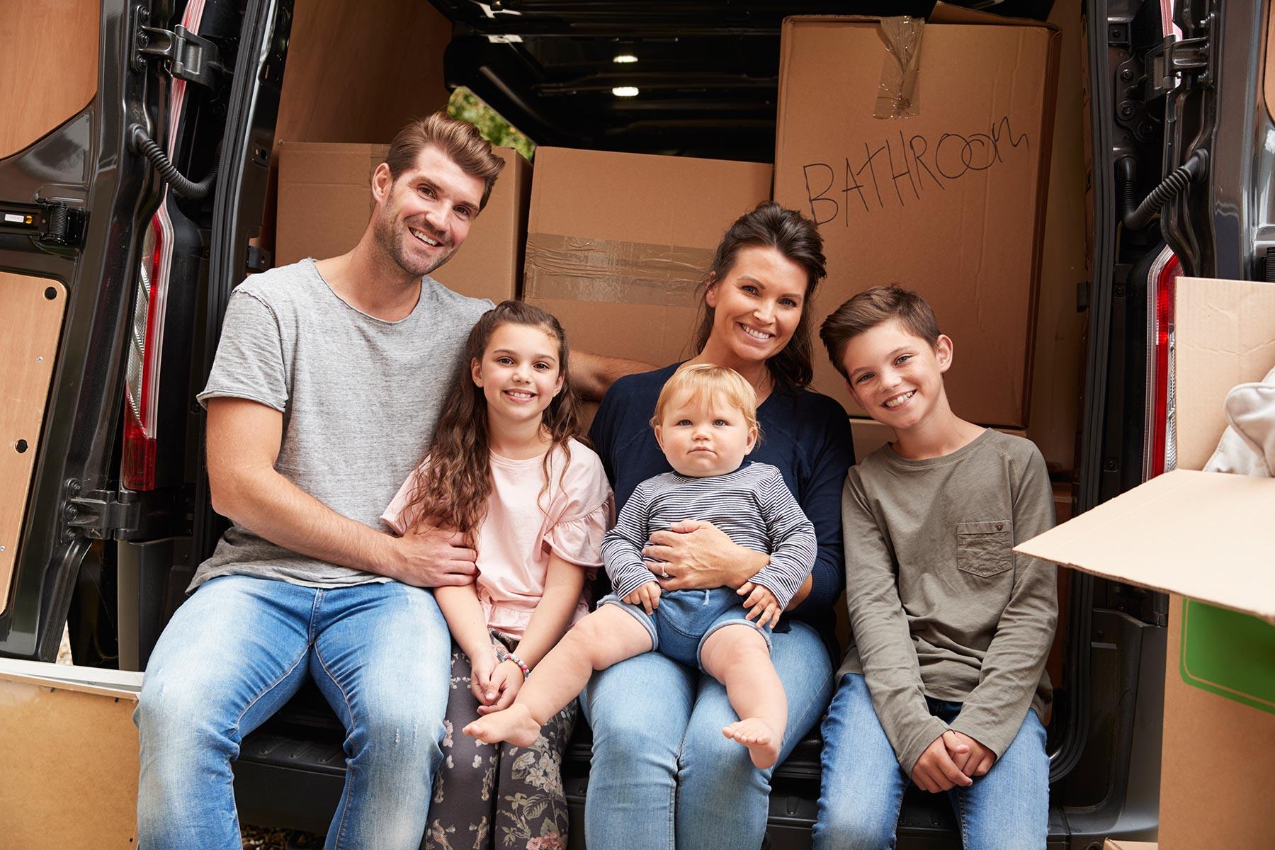 family-sitting-in-back-of-removal-truck-on-moving